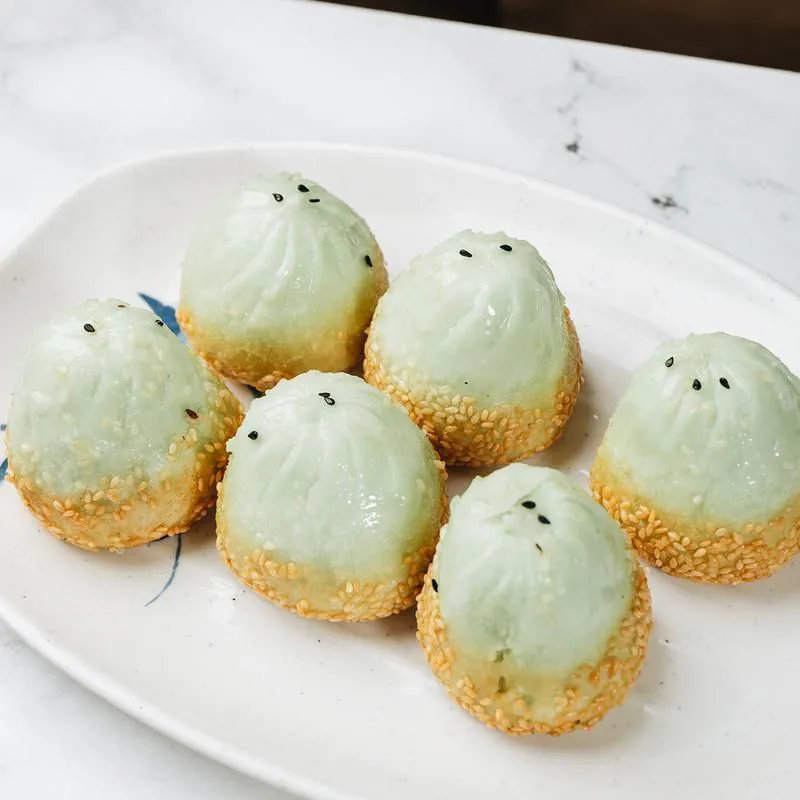 Green‑hued pan‑fried buns with sesame seeds on the bottom
