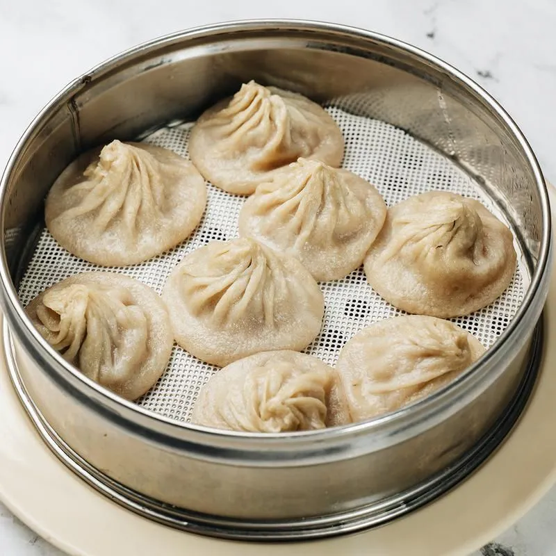 Steamed soup dumplings in a metal steamer basket