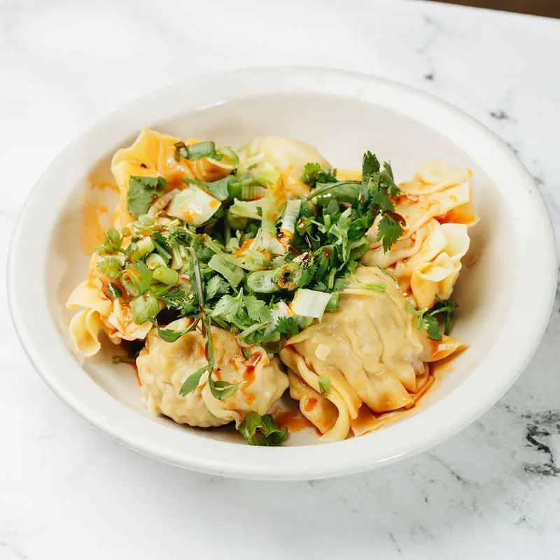 Spicy wontons topped with chopped green onion and cilantro