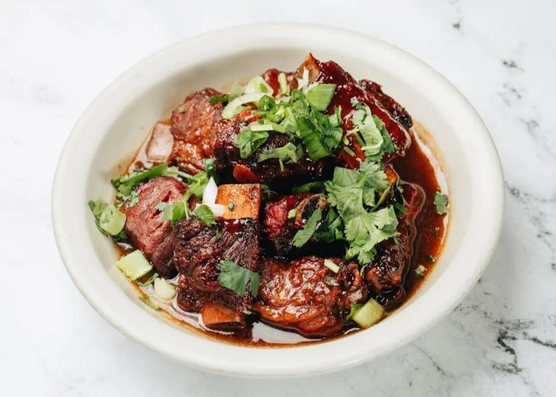 Braised pork ribs in rich sauce garnished with cilantro and green onions